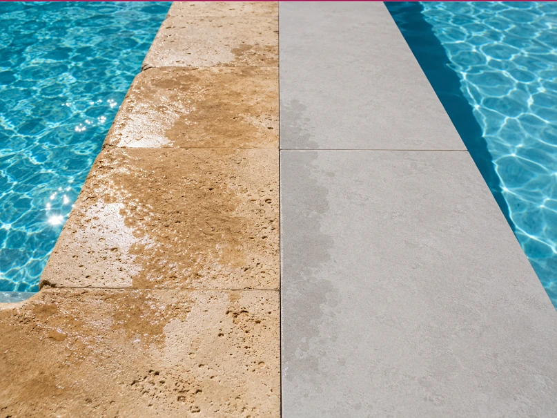 Pool edge showing travertine coping and porcelain coping side by side at the waterlines